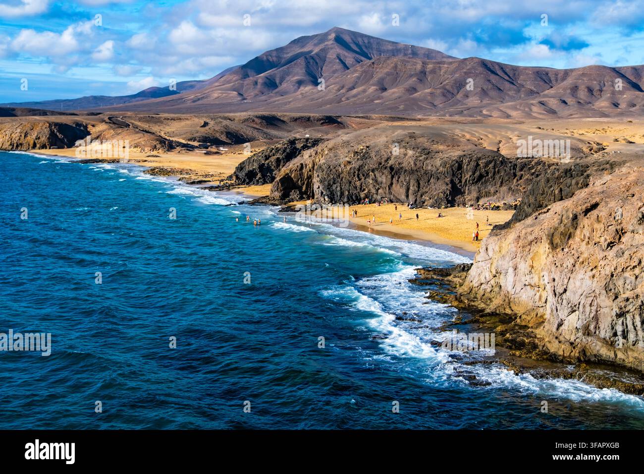 Vista panoramica aerea delle sabbie dorate di Playa Papagayo e delle acque turchesi circondate da scogliere rocciose. I visitatori si godono il bagno di sole e il nuoto sotto Foto Stock