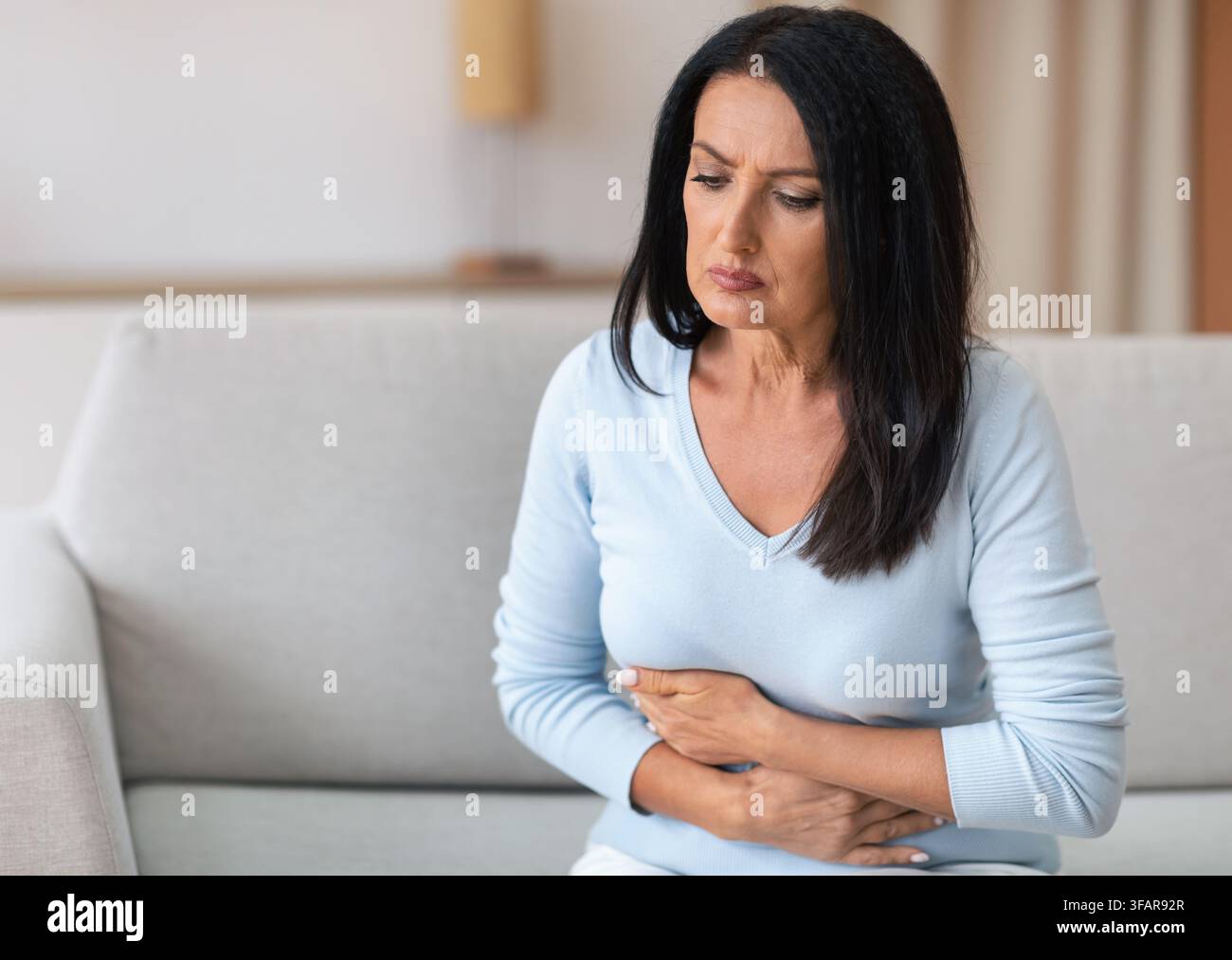 Donna matura che soffre di stomachache, toccando il ventre Foto Stock