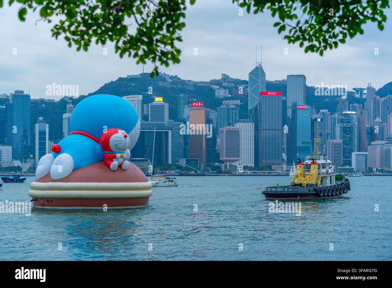 Vista dello skyline di Hong Kong e di una scultura gonfiabile gigante durante la Parata Acquatica nel Victoria Harbour di giorno, Isola di Hong Kong, Cina Foto Stock