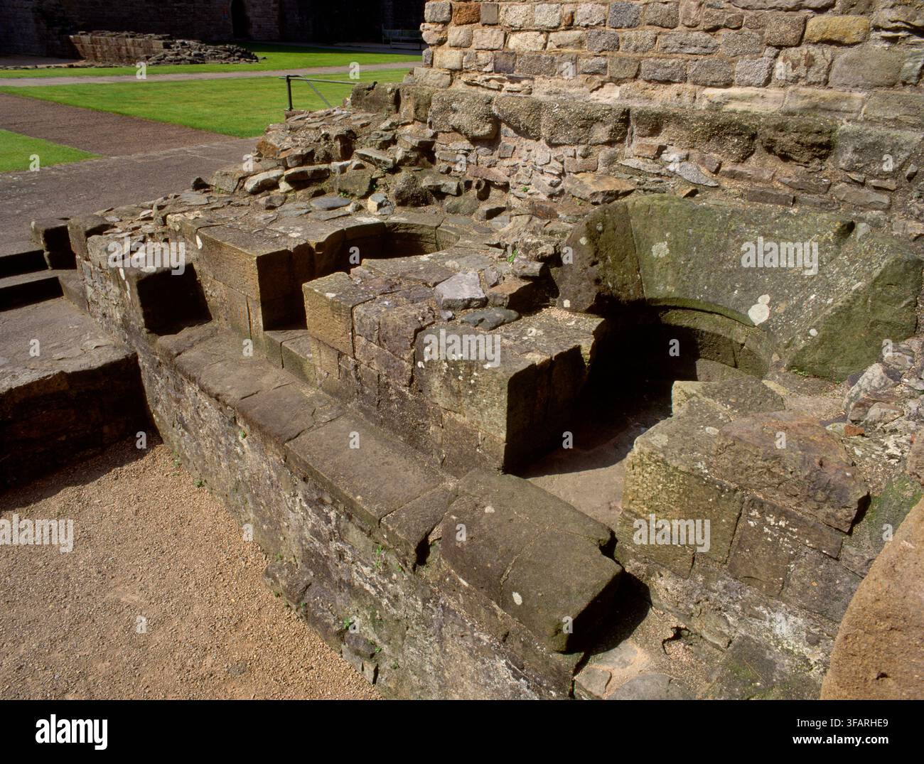 Vista a SW di focolari e posti a sedere per due calderoni di rame nella casa di ebollizione all'estremità ovest delle cucine del castello di Caernarfon, Gwynedd, Galles, Regno Unito. Foto Stock