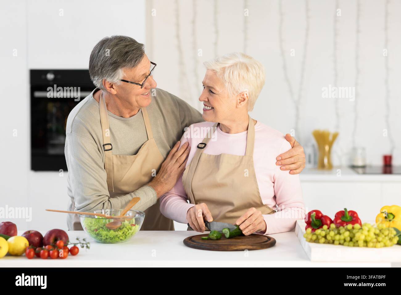 Amare marito anziano abbracciare moglie mentre si fa cena in cucina Foto Stock