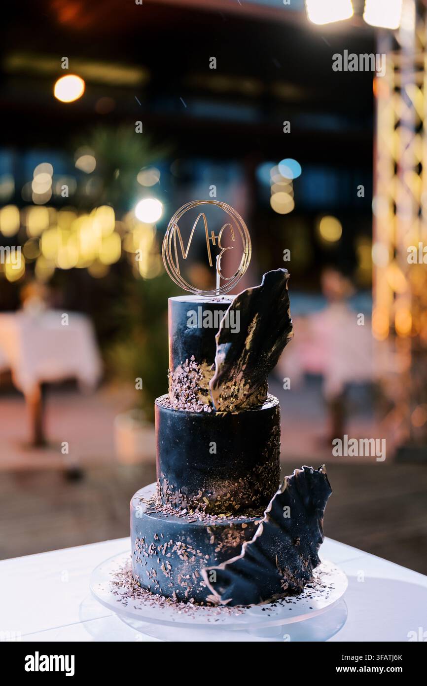 Elegante torta nuziale nera a tre piani con accenti decorativi Foto Stock
