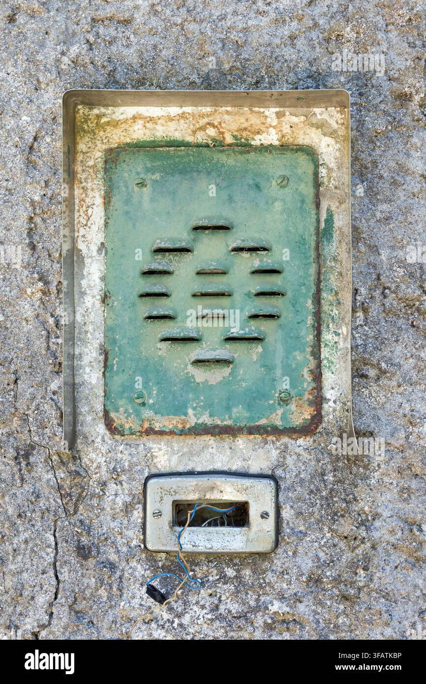 Prima di una campanella o interfono vintage e consumata incastonata in un muro di cemento invecchiato. Foto Stock