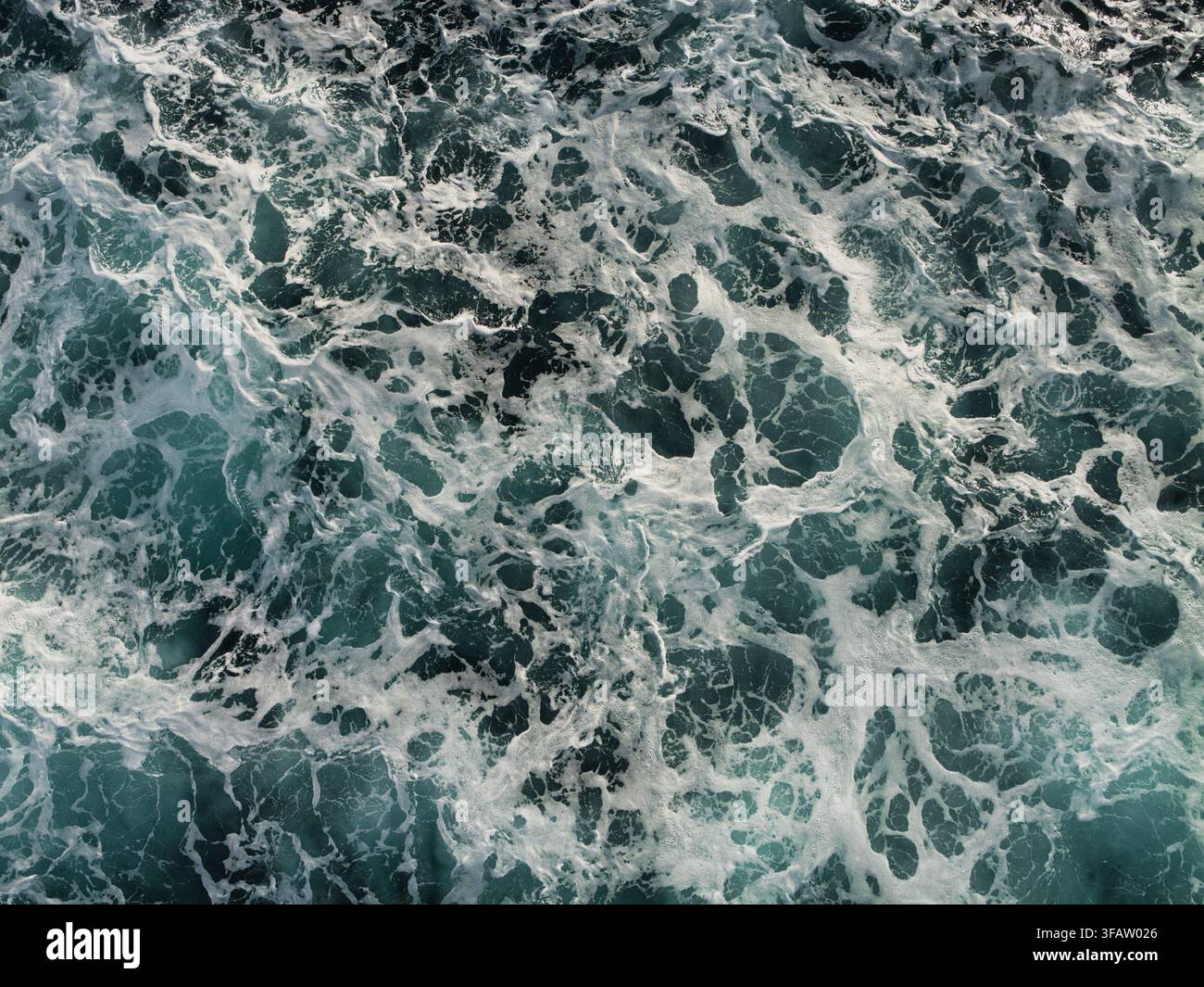 Onde schiumose formano un modello astratto energetico sull'acqua scura del Mare del Nord, Regno Unito Foto Stock