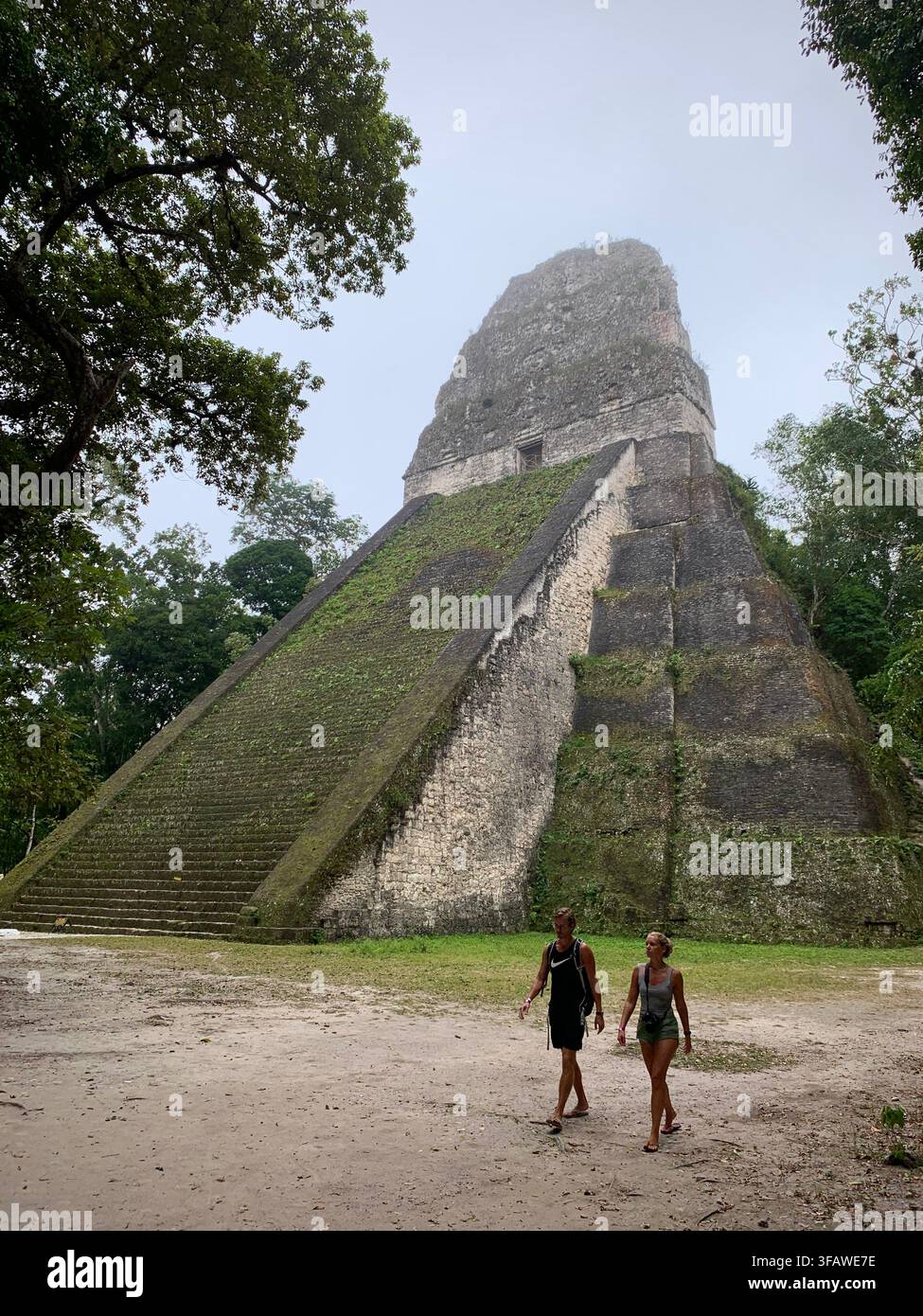 Flores, El Peten, Guatemala – 21 febbraio 2020: Due turisti passano davanti a una piramide Foto Stock