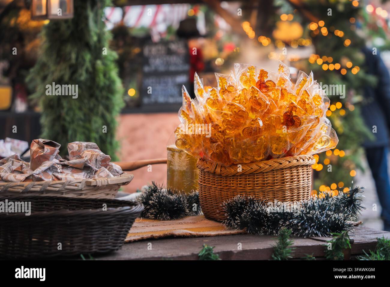 Lecca-lecca tradizionali a forma di gallo ricoperti di zucchero avvolti in un cesto di vimini su uno stand decorato al mercato di Natale di Riga, creando una texture festosa, fatto a mano Foto Stock