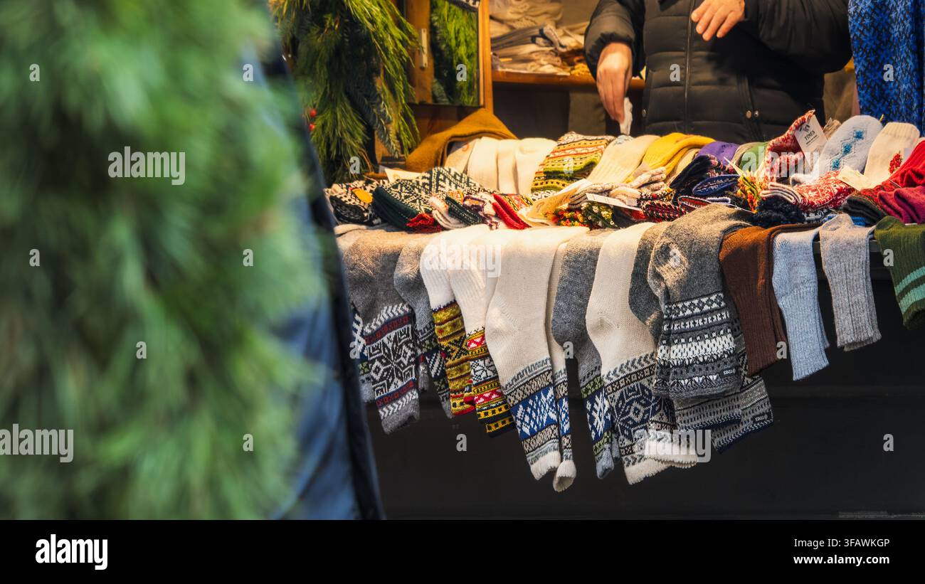 Calzini invernali lavorati a maglia sono esposti in calzini a fantasia e piccoli indumenti disposti su un tavolo del mercato natalizio di Riga per l'artigianato fatto a mano, Lettonia Foto Stock