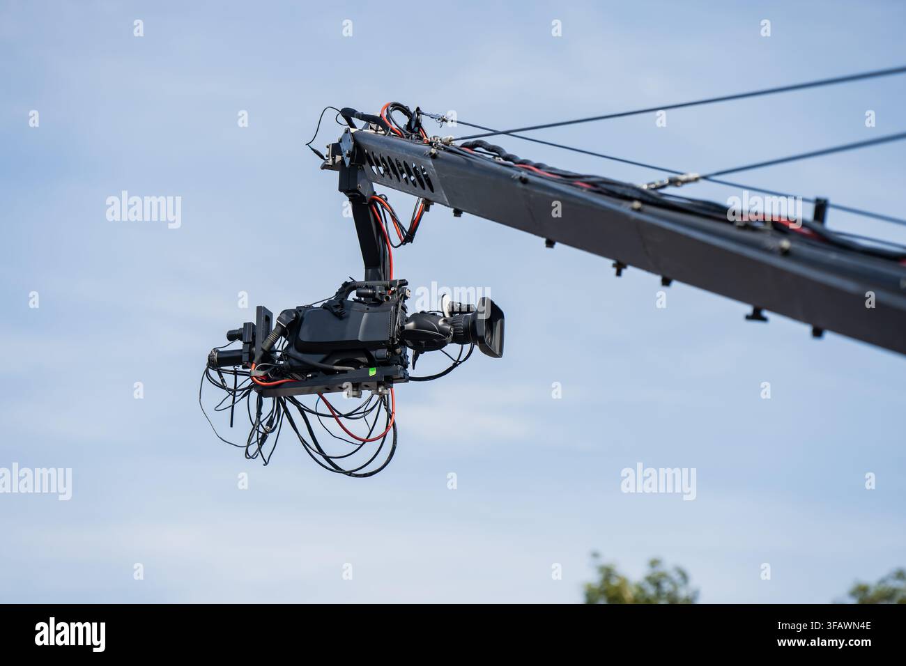 Rig per telecamera per trasmissione televisiva attaccato al braccio di una gru industriale che opera in un ambiente di produzione mediatica all’aperto Foto Stock