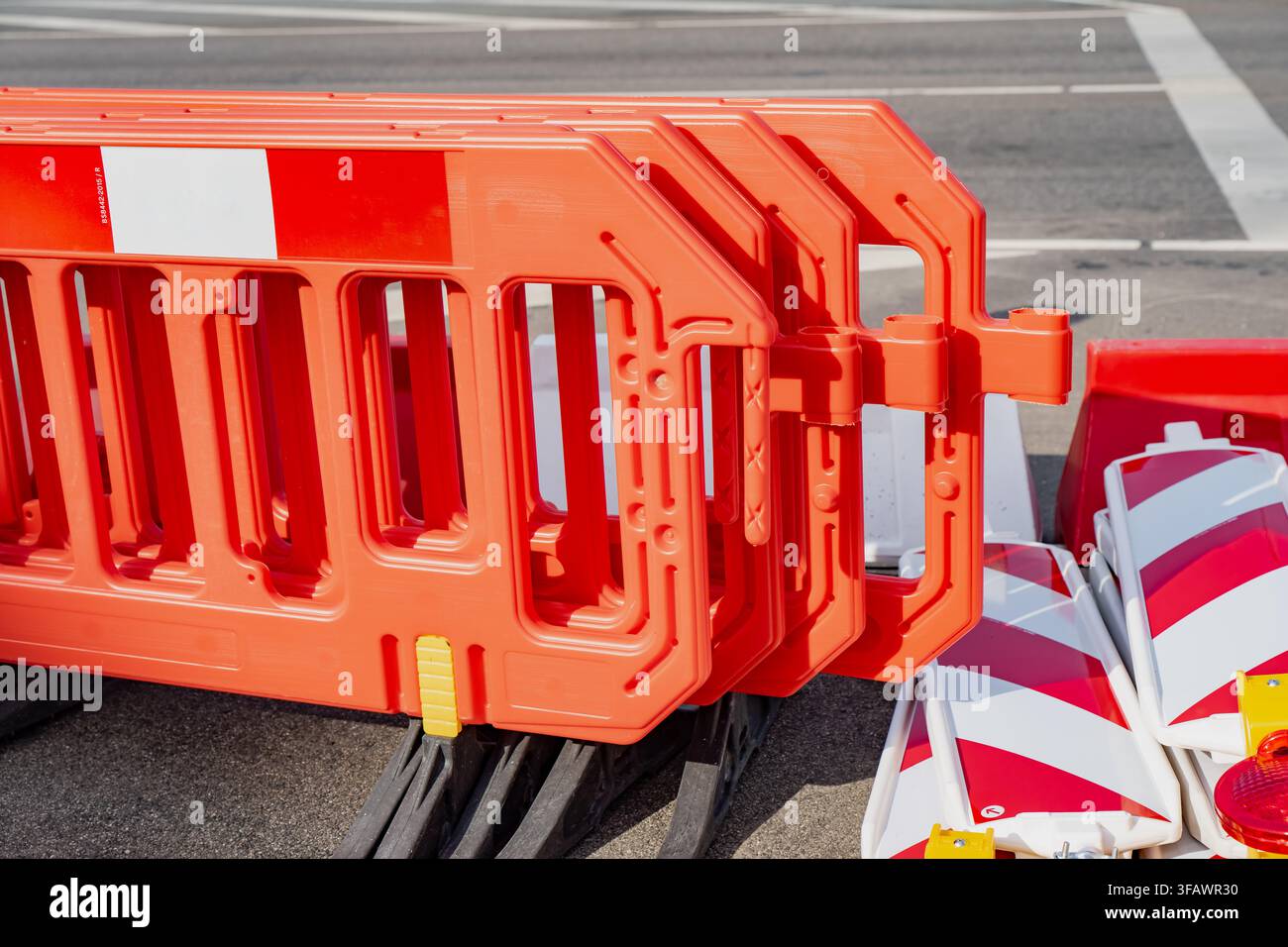 Prima vista di barriere di controllo del traffico pedonale in plastica arancione con cerniere a spillo interbloccanti e piedi di base stabili in composito nero in una zona di cantiere Foto Stock