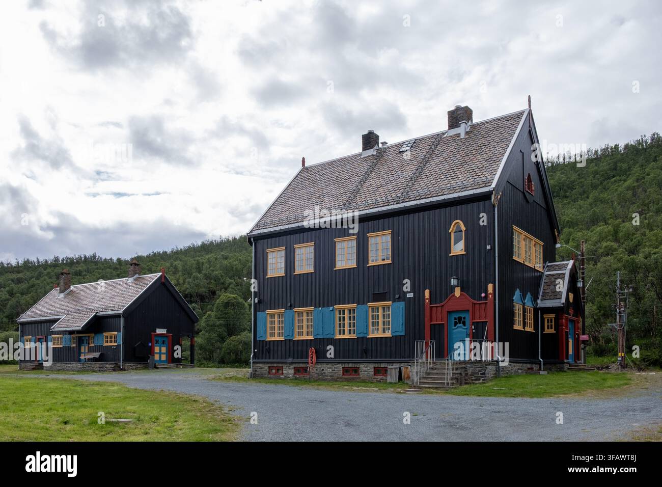 Edifici storici in legno nero con accenti colorati a Dovrefjell, Norvegia, sotto cieli nuvolosi drammatici. Foto Stock