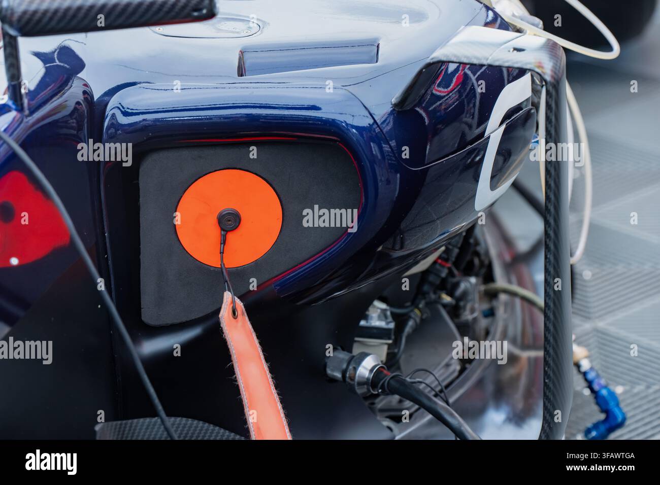 Primo piano di un interruttore elettrico di emergenza per auto da corsa di formula con anello di traino arancione brillante e meccanismo di cordino di sicurezza con spilla Foto Stock