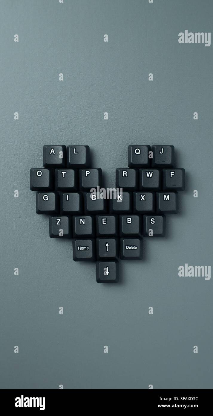 Forma a cuore creata con tasti della tastiera su sfondo grigio minimale. adatto per tecnologia, appuntamenti online, comunicazione digitale, amore e relazioni Foto Stock