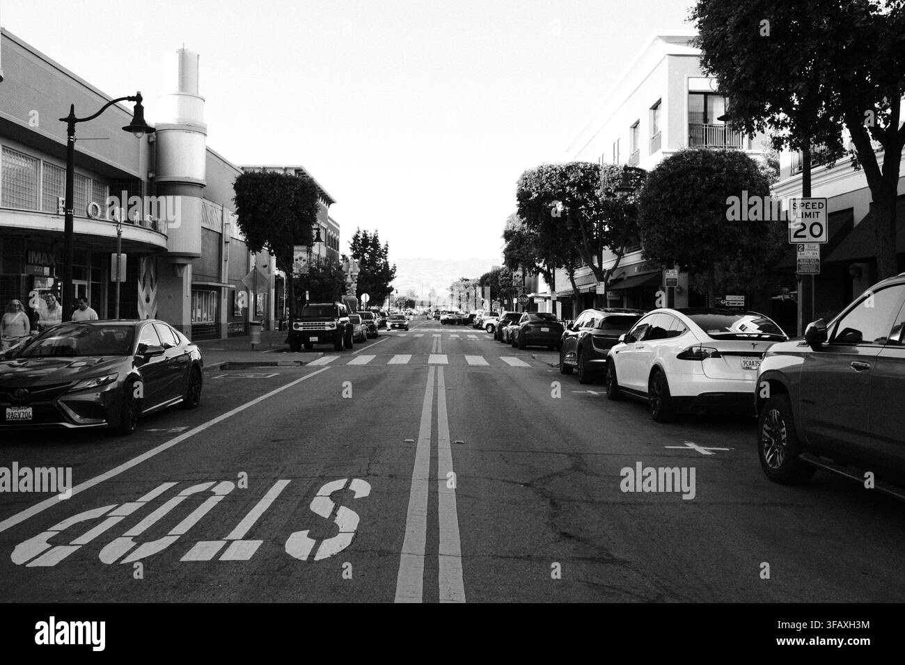 Via del centro di Long Beach, California, con una grande segnaletica STOP sul marciapiede, attraversamento pedonale, auto parcheggiate e limite di velocità indicato di 20 mph. Foto Stock