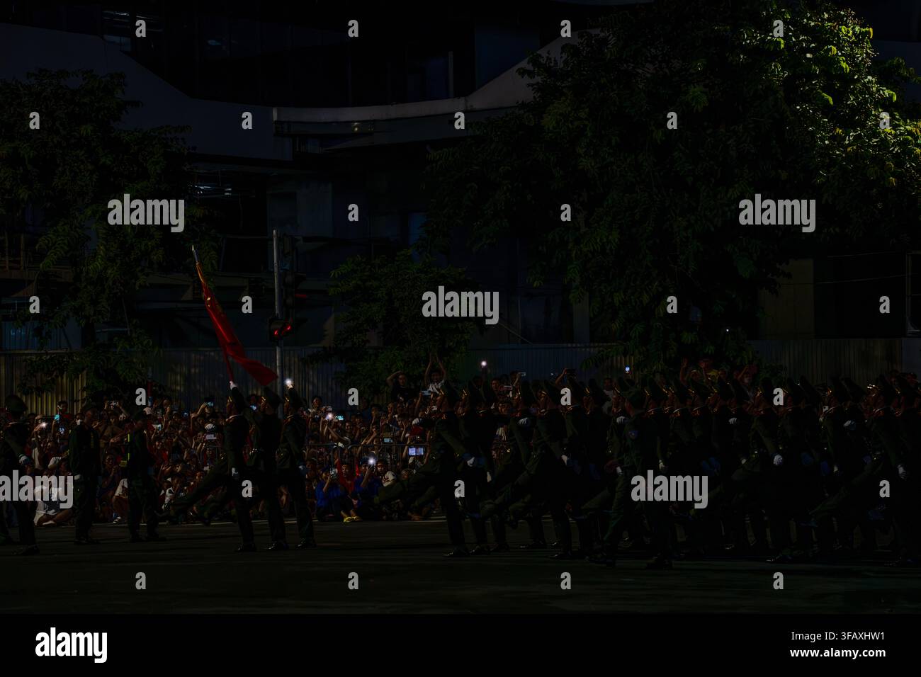 Soldati in silhouette che marciano con bandiera nella quasi oscurità su Van Cao, Hanoi di notte Foto Stock