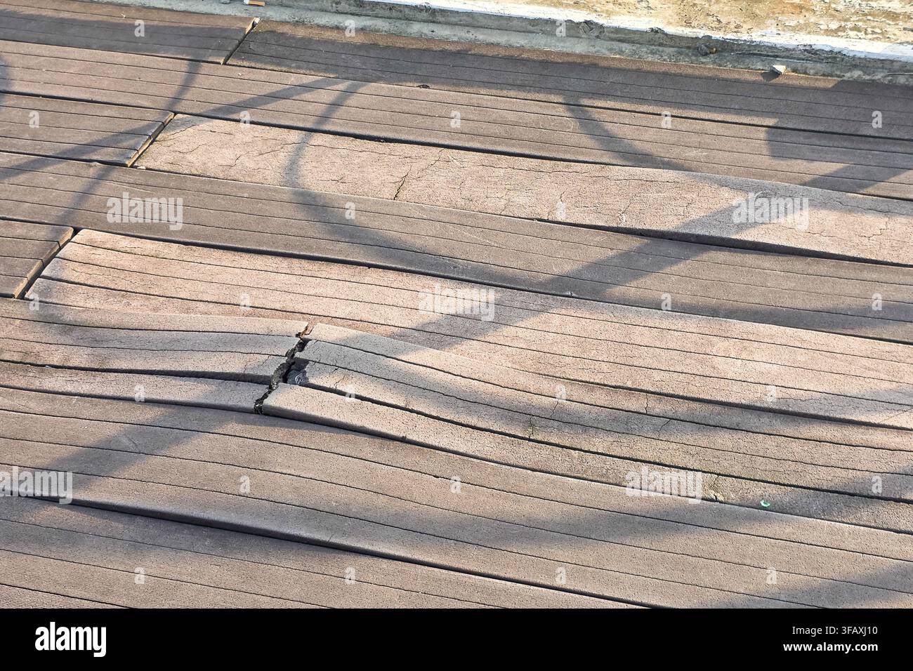 Piattaforma in legno duro deformata e danneggiata a causa dell'esposizione prolungata alla pioggia e alle intemperie estreme Foto Stock