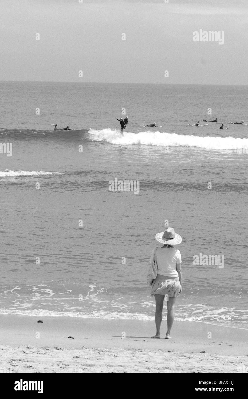Un bagnante solitario osserva le onde che si infrangono sull'Oceano Pacifico alla Malibu Surfrider Beach di Malibu, in California. Foto Stock