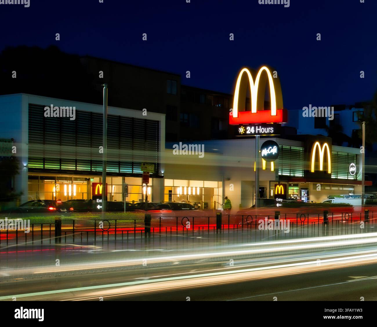 Paesaggio urbano di un ristorante McDonald’s con archi dorati luminosi e cartello 24 ore su 24, Sydney, Australia. Foto Stock