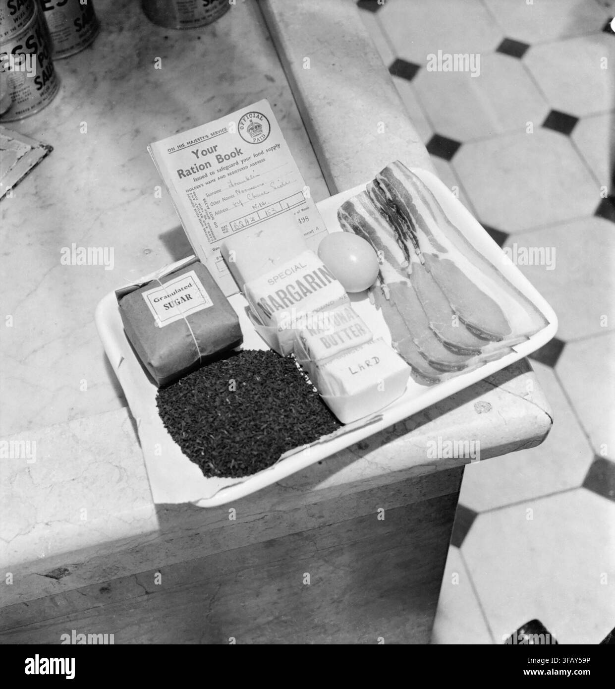 Vassoio contenente una razione prenota e la razione settimanale di zucchero, tè, margarina, "burro nazionale', strutto, uova e pancetta e formaggio come emesso per un adulto in Gran Bretagna durante il 1942. Una vista di un vassoio contenente la razione di prenotare per un signor Norman Franklin e la sua razione settimanale di zucchero, tè, margarina, "burro nazionale', strutto, uova e pancetta e formaggio. Foto Stock