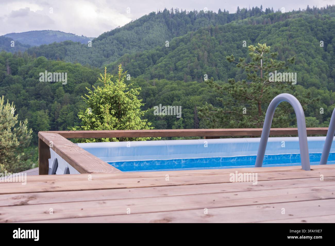 Una tranquilla piscina all'aperto si affaccia su pendici montuose densamente boschive, offrendo un paesaggio scenografico per il relax e il turismo rurale. Foto Stock
