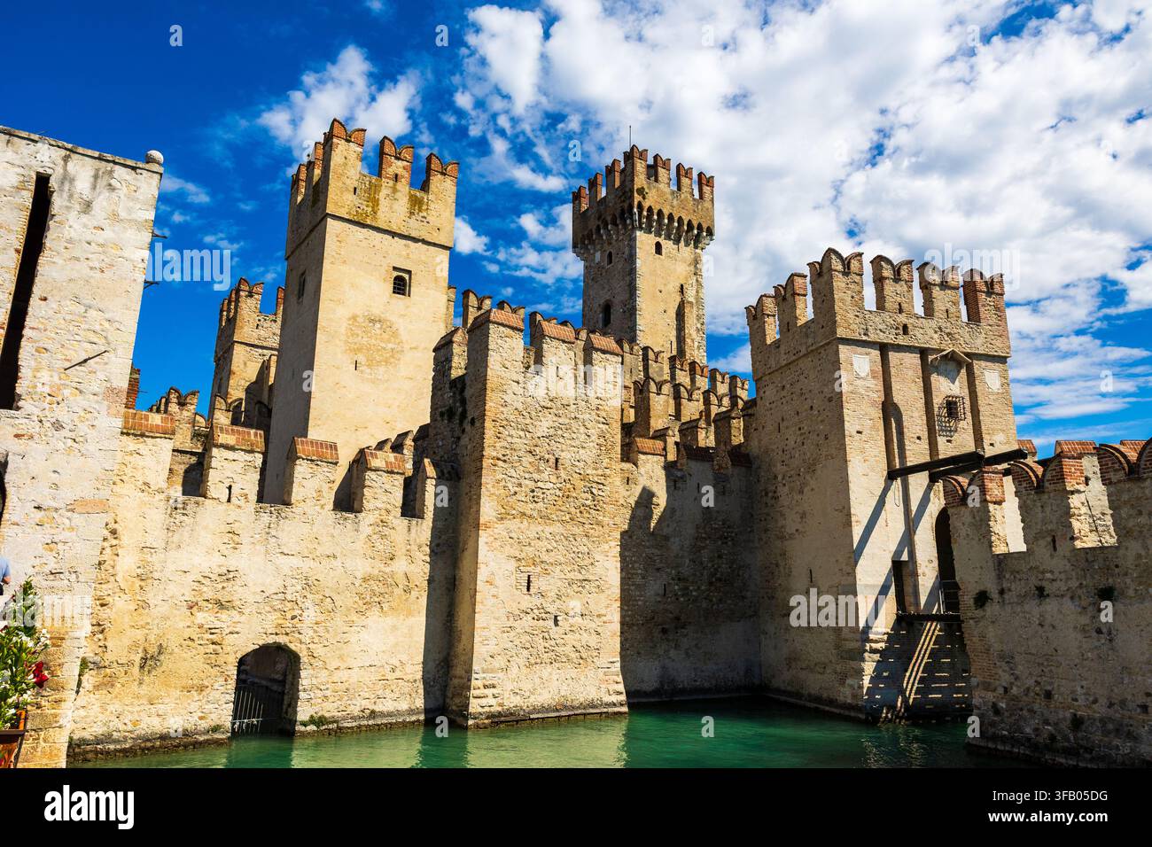 Facciata illuminata dalla luce del sole della Rocca Scaligera di Sirmione dal porto, una fortezza medievale e unico punto di accesso al centro storico della città Foto Stock