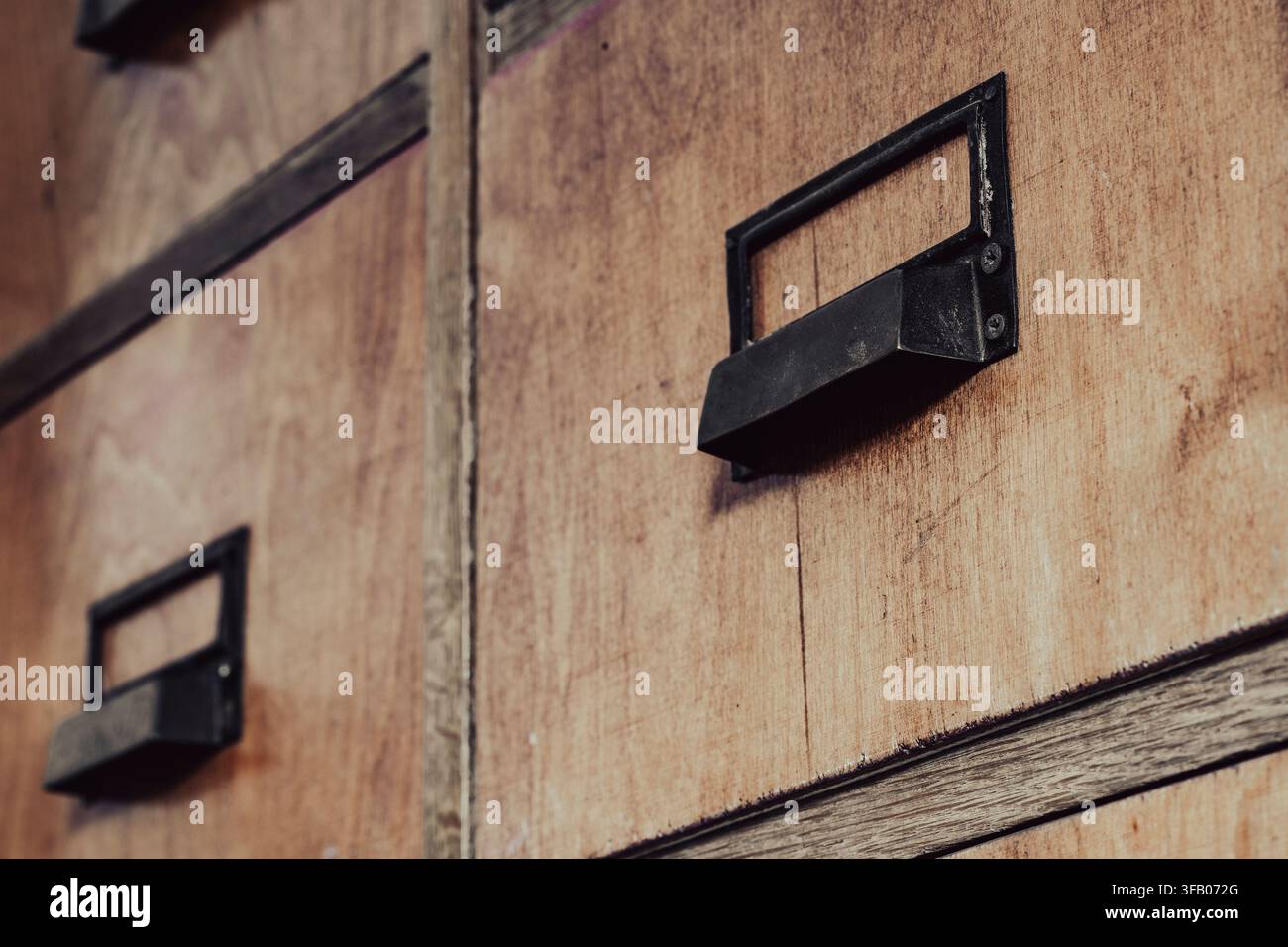 Cassetti vintage di un schedario in legno con maniglie metalliche. Primo piano di cassetti rustici in legno di un catalogo a schede o di un indice di biblioteca con maniglie metalliche nere antiche Foto Stock