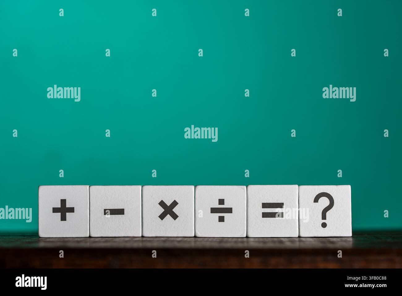 Simboli matematici e punto interrogativo su blocchi di legno, primo piano. Sei cubi di legno bianchi con simboli matematici stampati più meno moltiplicare dividere uguale Foto Stock