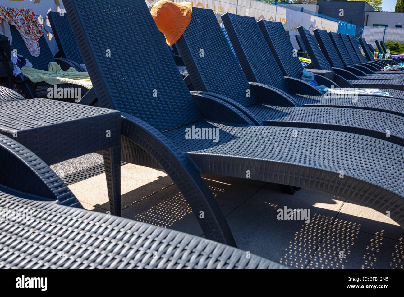 Filiera di sedie a sdraio blu vuote allineate accanto alla piscina in un resort di lusso, concetto di relax in vacanza estiva e dotazioni alberghiere Foto Stock