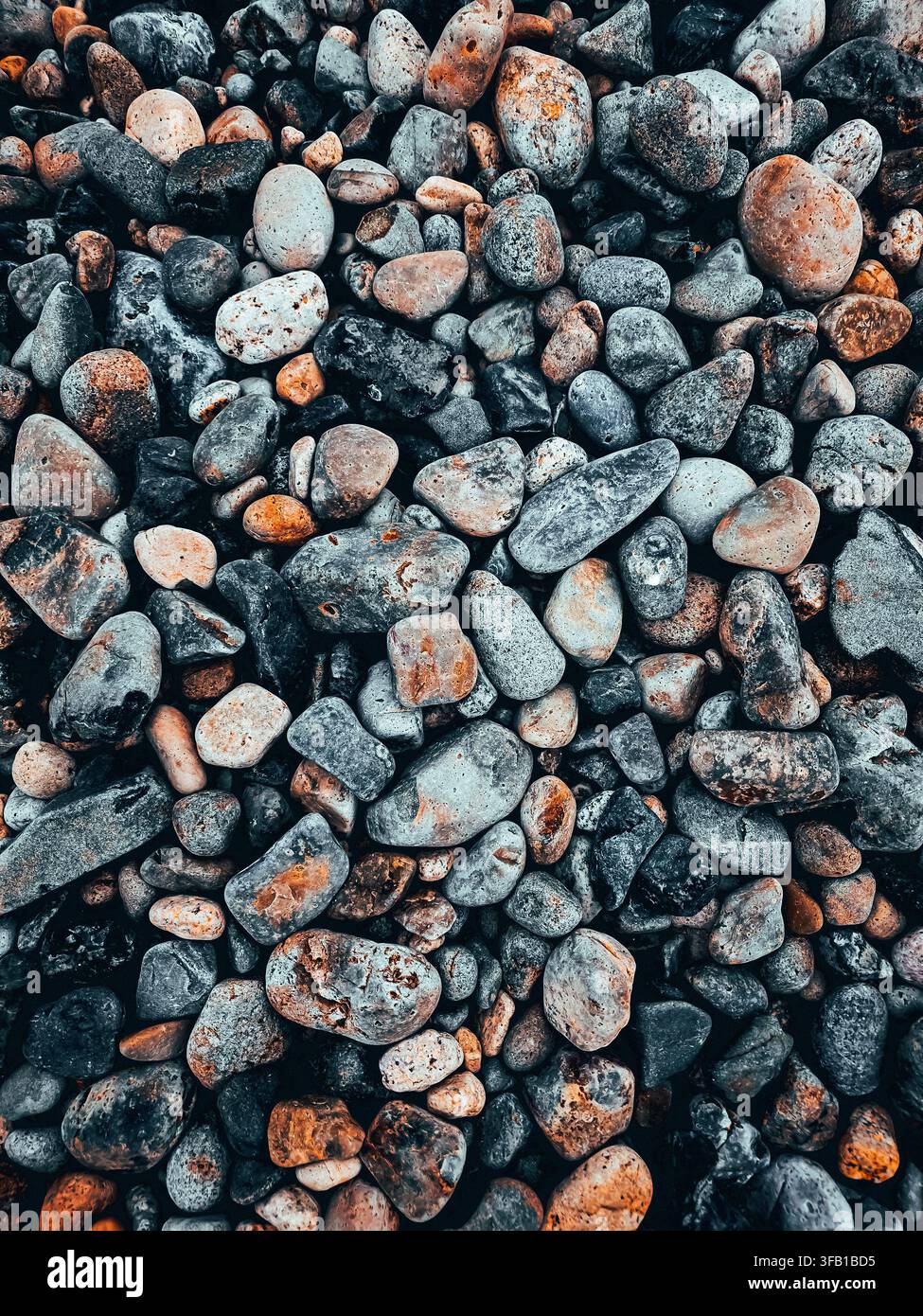 Vista dall'alto texture di ciottoli lisci e colorati e pietre fluviali come sfondo per carta da parati a tutto schermo. Foto Stock