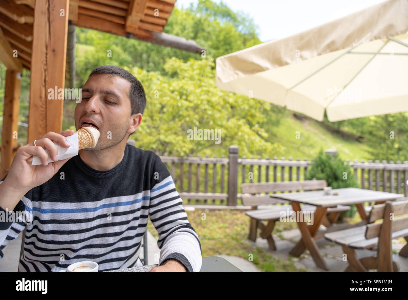 Uomo che gusta un cono di gelato all'aperto a Sottoguda Foto Stock