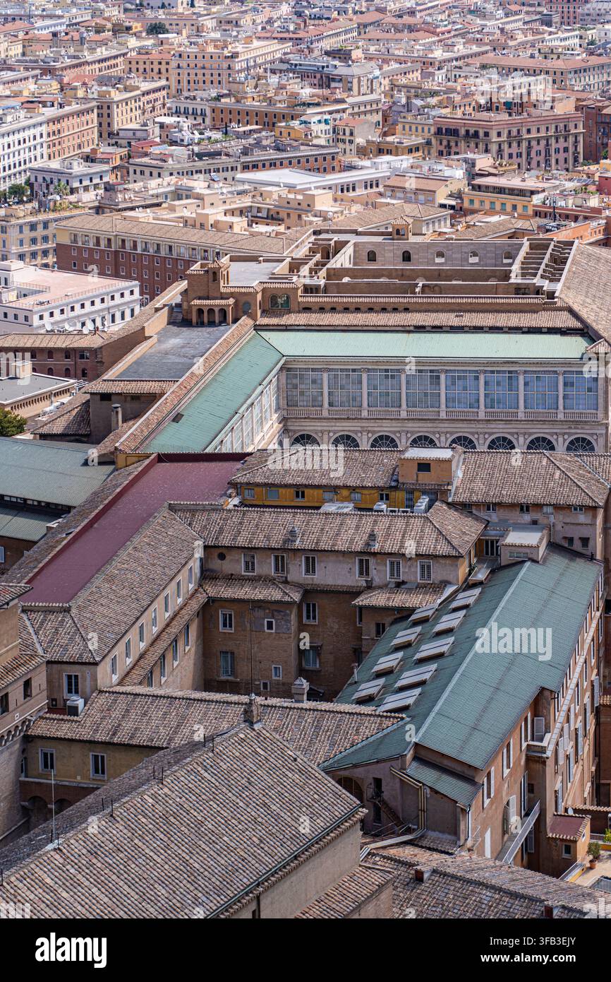 Vista elevata dell'architettura vaticana con tetti storici, cortili ed edifici monumentali nella Città del Vaticano, circondata dalle dense terre urbane Foto Stock