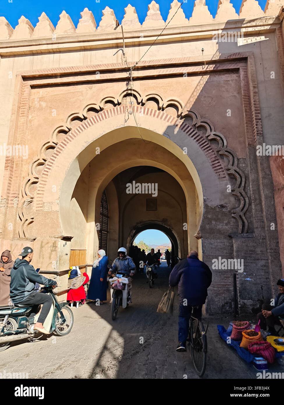 Porta storica nella medina di Marrakesh con persone, biciclette e motociclette. - Immagine stock catturata con smartphone