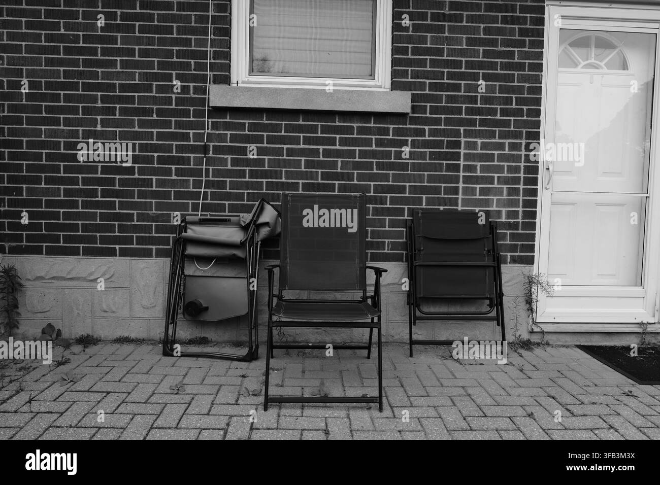 Sedie da patio all'aperto contro il muro di mattoni di una casa accanto a una porta bianca, Ontario, Canada. Foto Stock