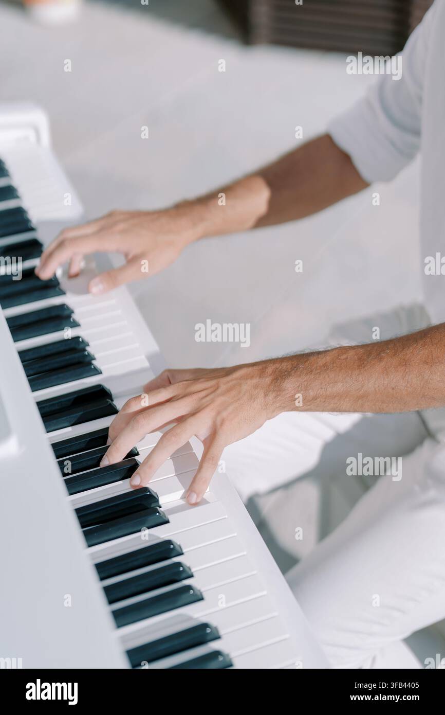 Primo piano di mani che suonano un pianoforte bianco all'aperto Foto Stock