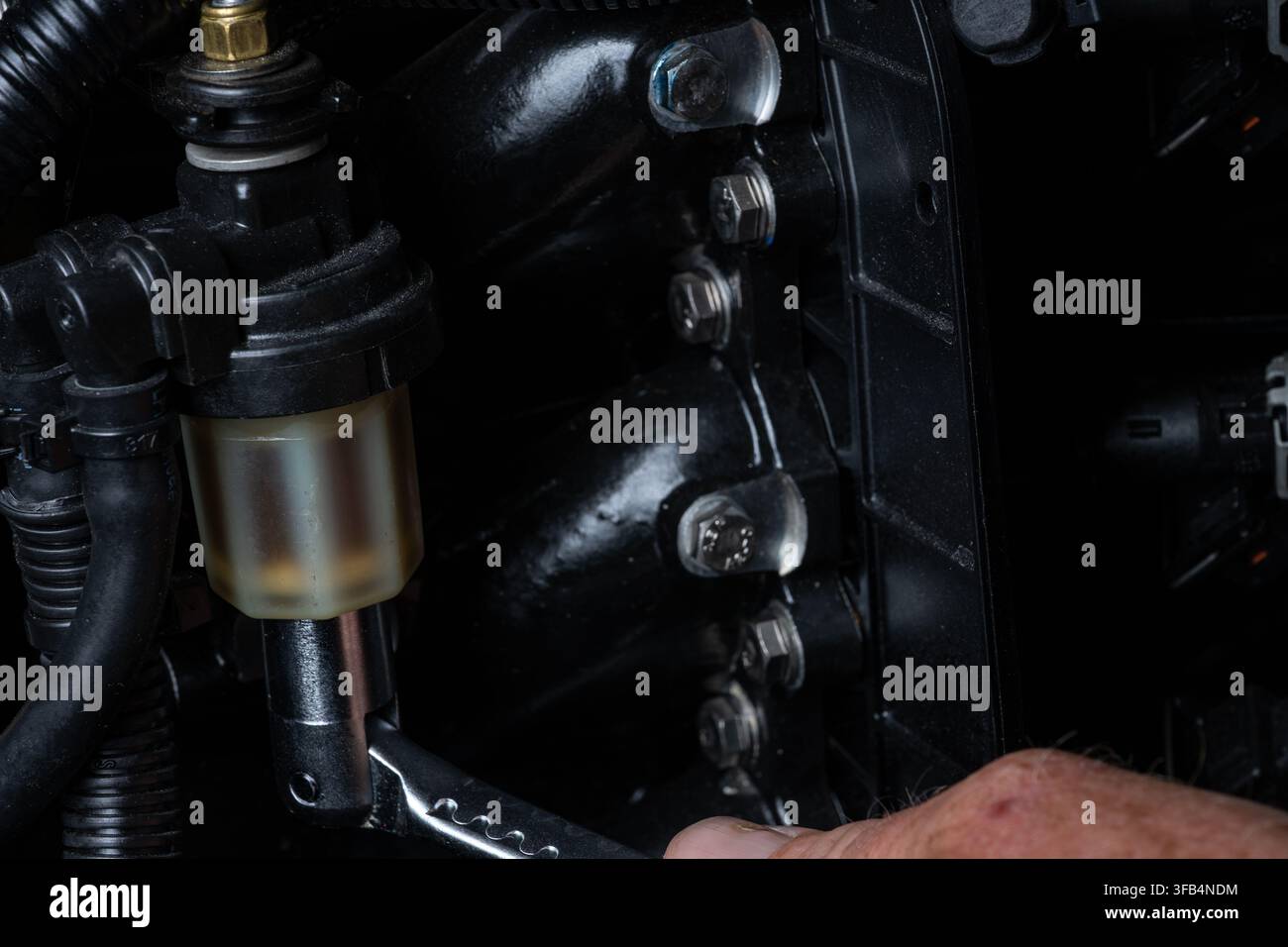 Prima vista di un meccanico che svita e rimuove il gruppo filtro carburante su un motore fuoribordo durante la manutenzione e il servizio di routine. Vista dettagliata Foto Stock
