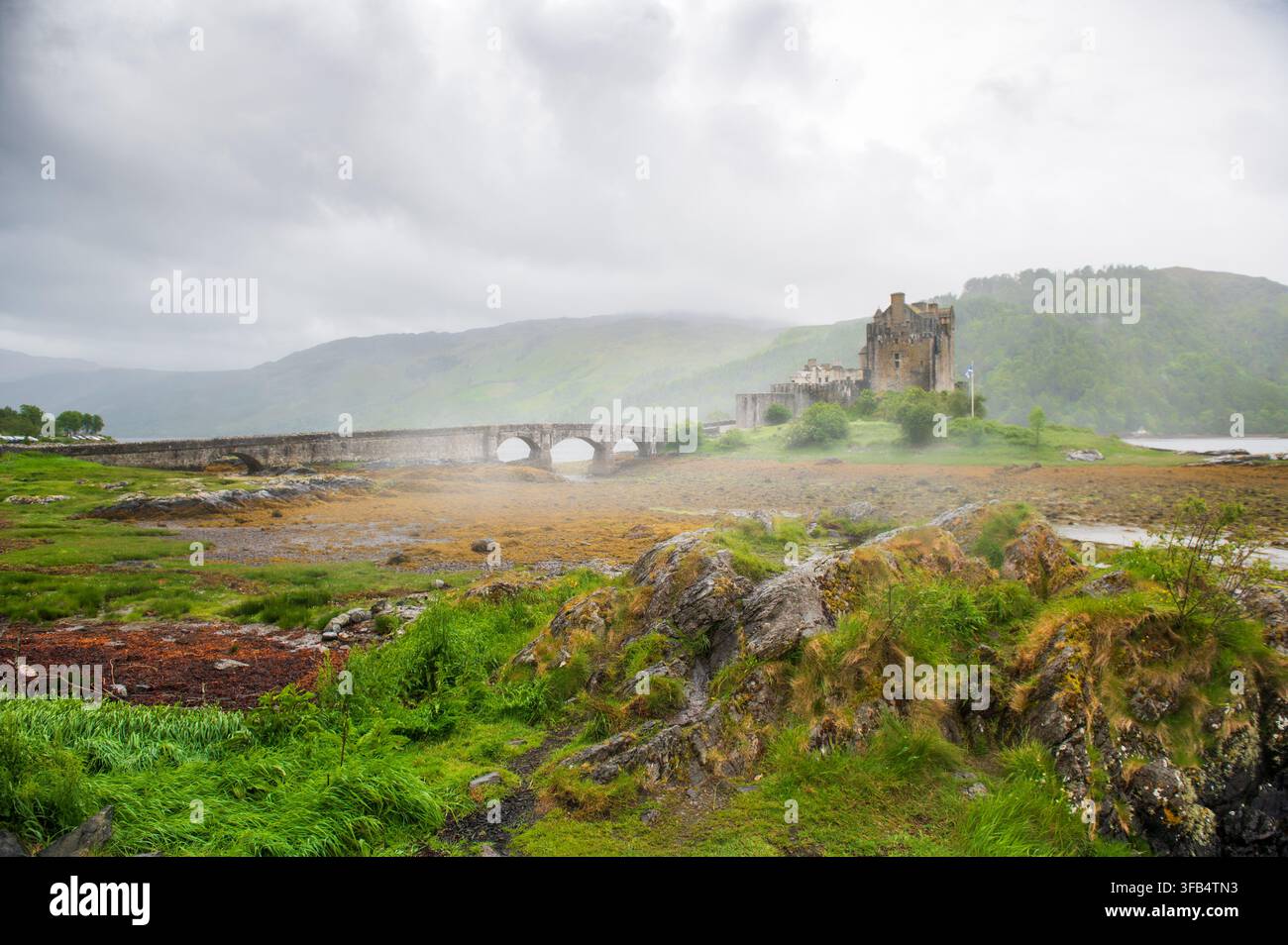 Ampia veduta del famoso castello di Eilean Donan e del suo ponte in una giornata nebbiosa, Scozia Foto Stock