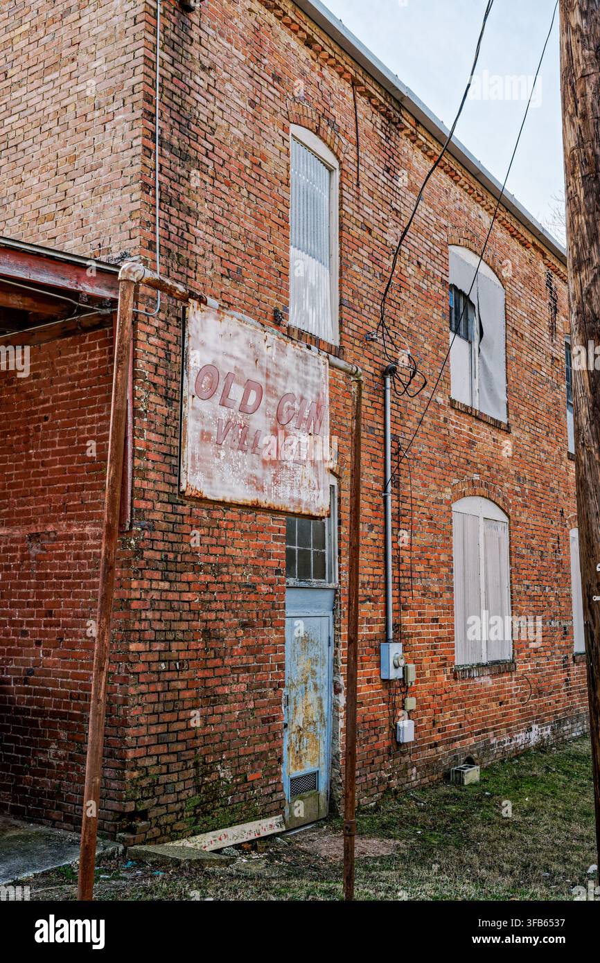 Antico edificio in mattoni rossi vintage a due piani con un'insegna per Old Gin Village che è stato abbandonato a Wetumpka, Alabama, USA. Foto Stock