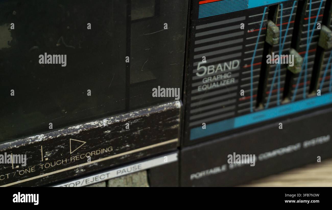 Estremo primo piano che rivela i dettagli intricati di un equalizzatore grafico a cinque bande e di un vano cassette polveroso su un apparecchio audio portatile antico Foto Stock