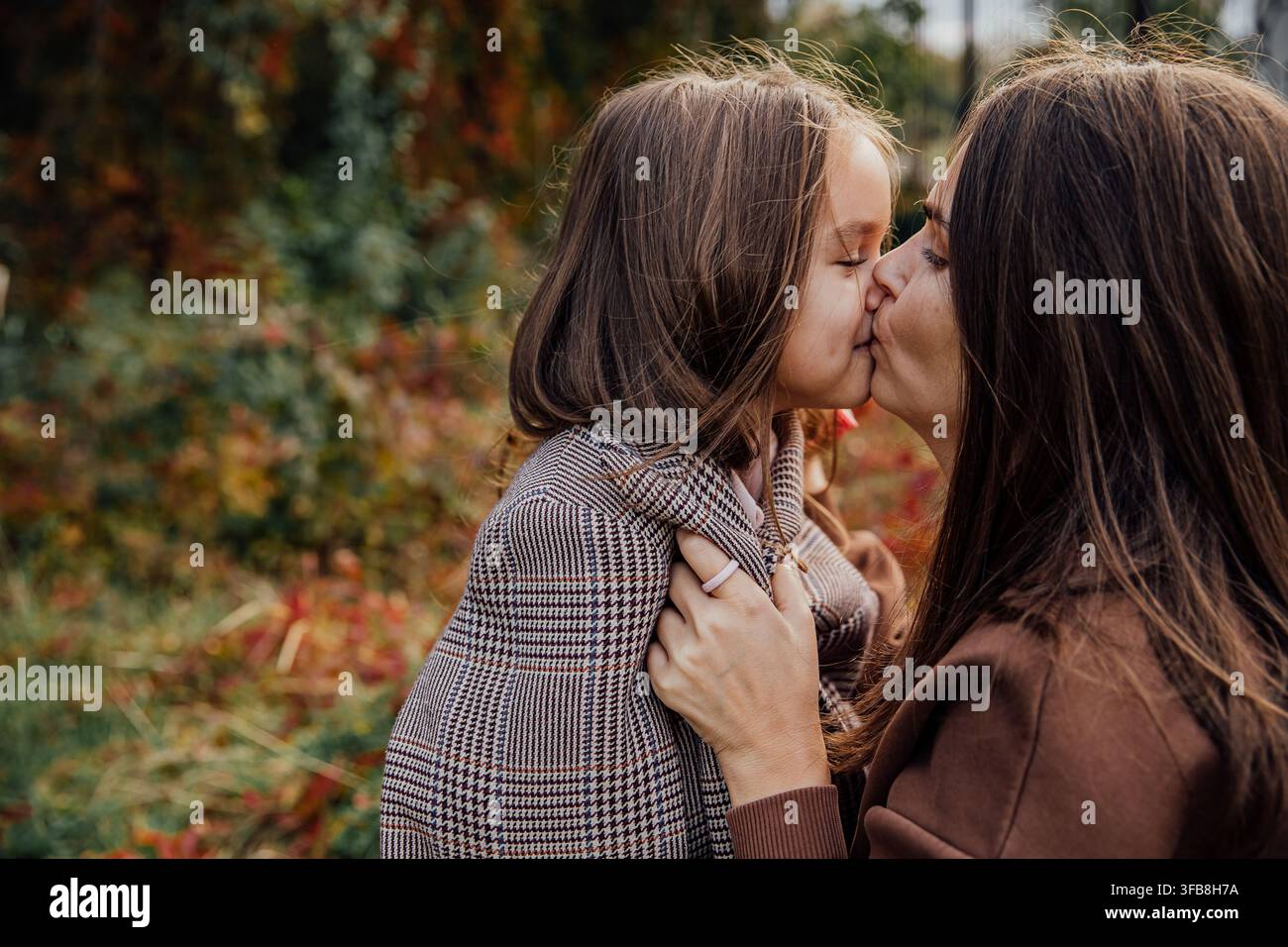 Madre e figlia condividono un momento d'amore all'aperto nella stagione autunnale. Foto Stock