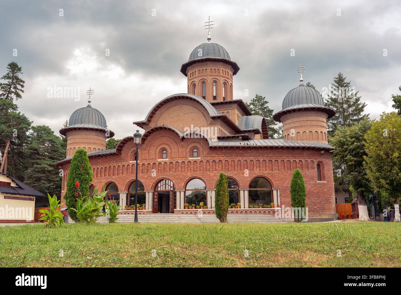 Cattedrale a cupola in mattoni rossi del monastero di Curtea de Argeș nella contea di Argeș, Romania sotto un cielo nuvoloso Foto Stock