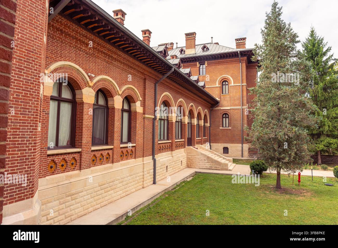 Ala monasteriale ad arco in mattoni rossi e giardino del monastero di Curtea de Argeș nella contea di Argeș, Romania Foto Stock