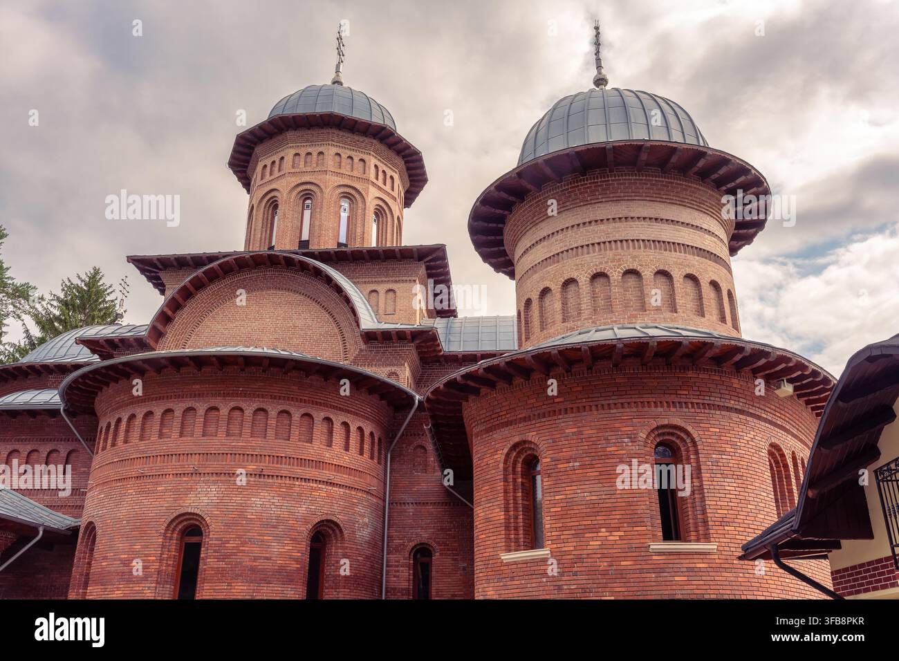Vista ravvicinata di cupole e croci in mattoni rossi del monastero di Curtea de Argeș nella contea di Argeș, Romania Foto Stock