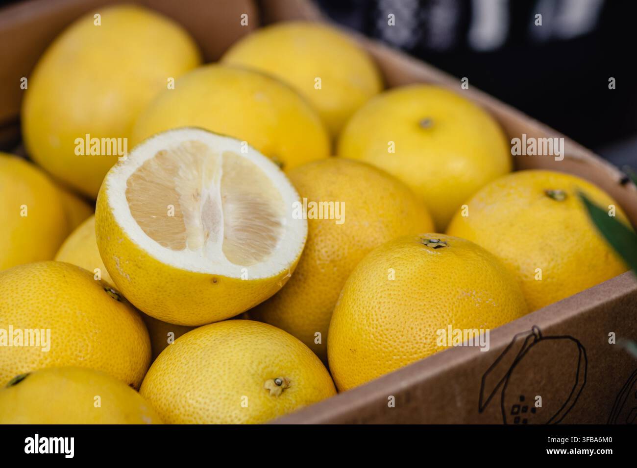 Pomelo fresco o frutto agrumato Sweetie, con un frutto tagliato a metà in un mercato di frutta e verdura Foto Stock