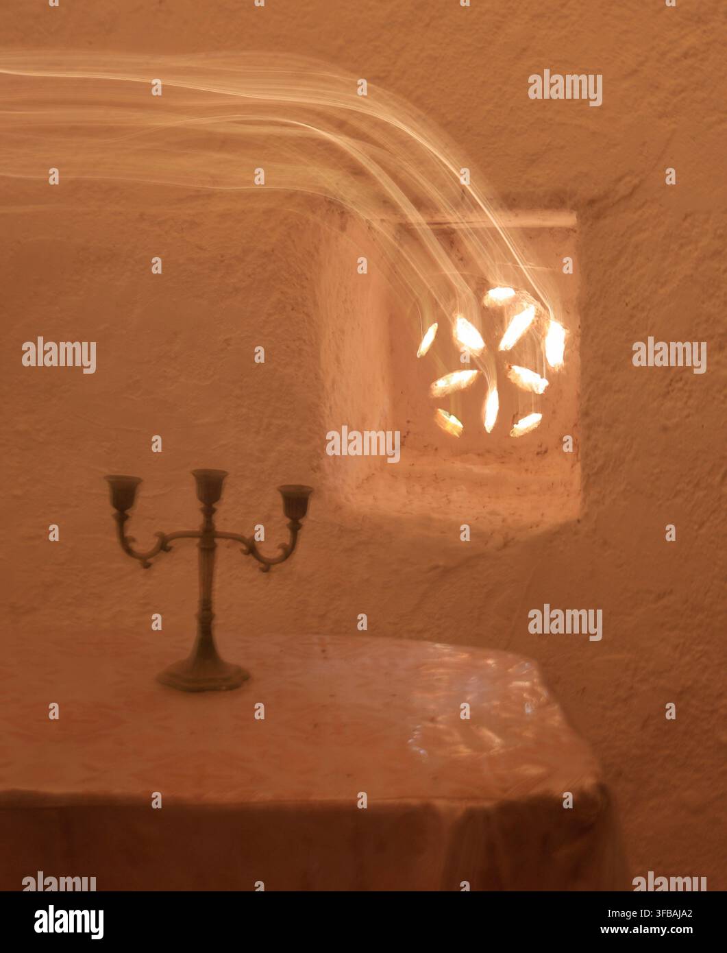 Candelabro antico su un tavolo accanto a una finestra decorativa con strisce di luce, Grecia Foto Stock