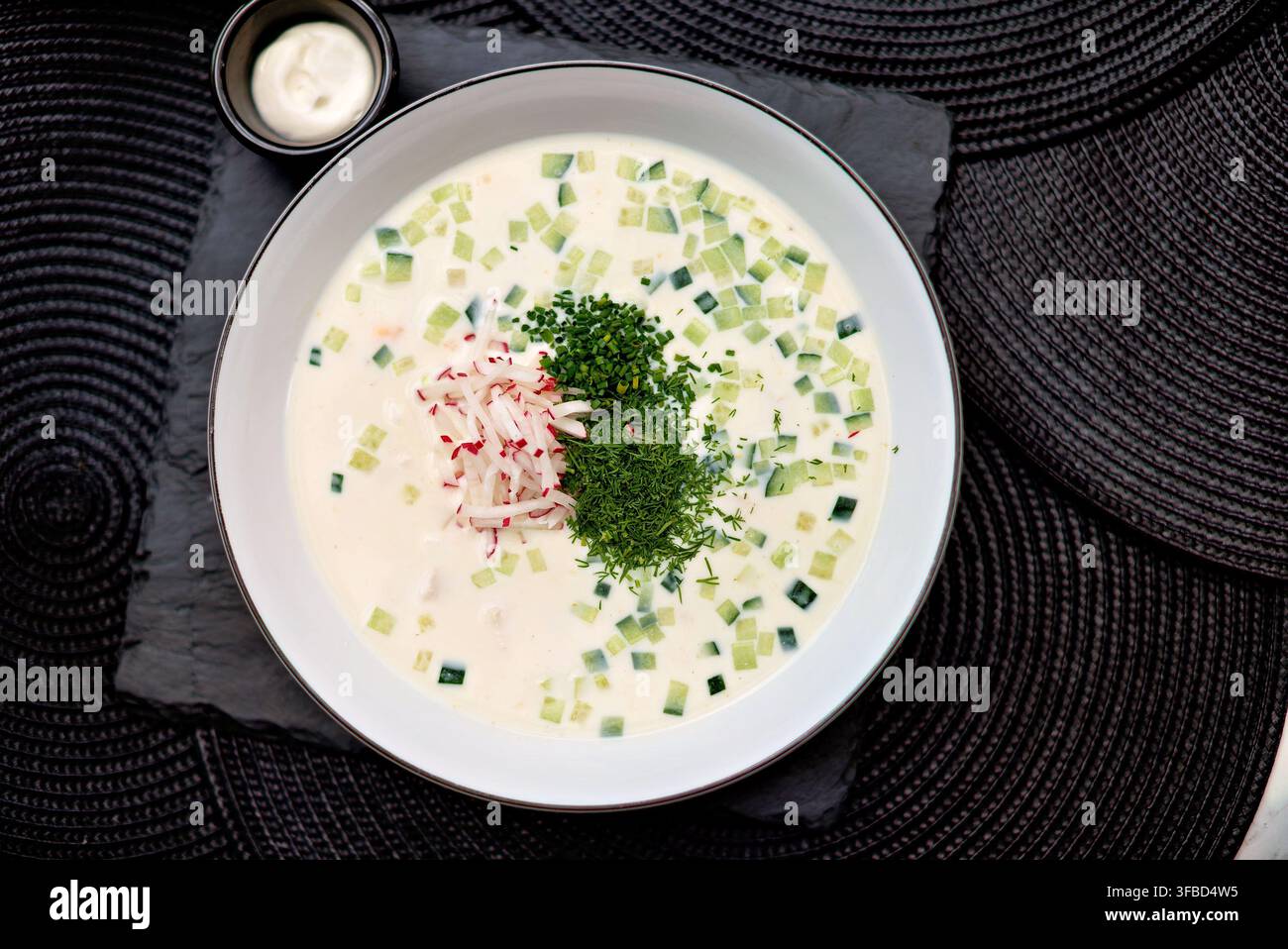 Zuppa fredda servita in ciotola bianca con erbe fresche e verdure Foto Stock