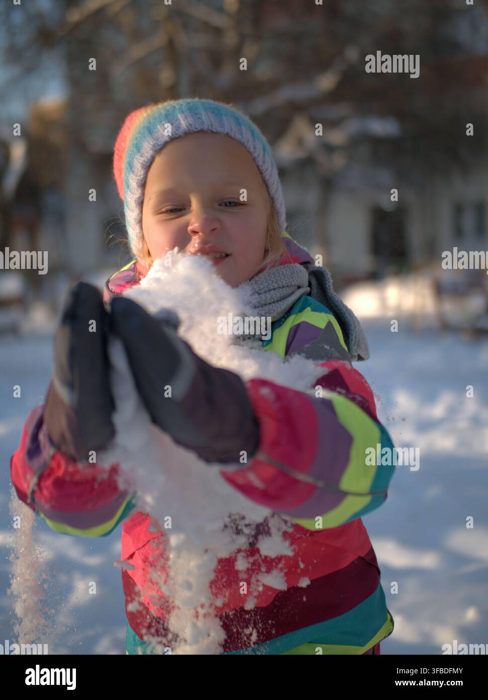 Ragazza che soffia la neve dalle sue mani guantate Foto Stock