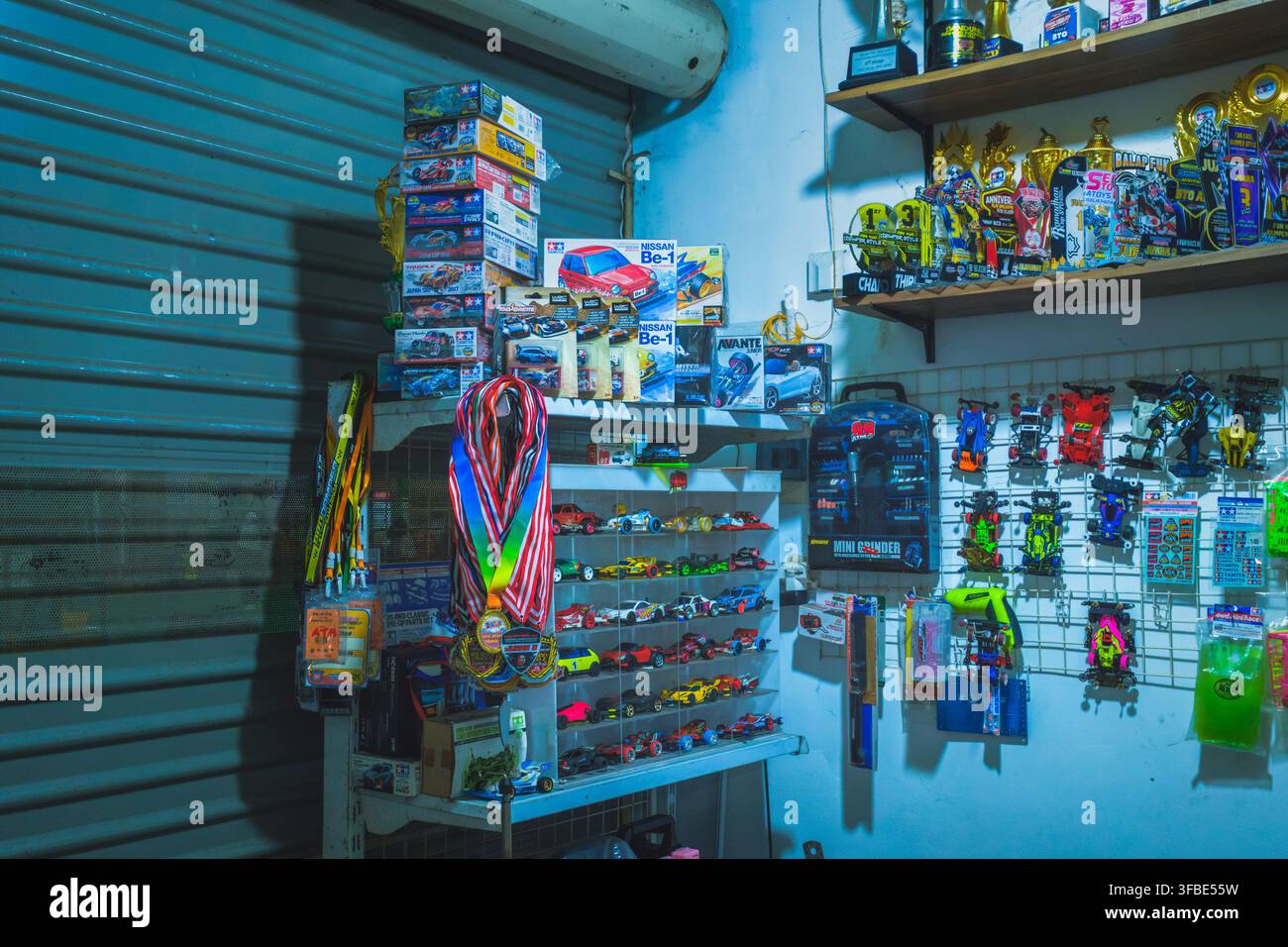 Balikpapan, Indonesia - 25 luglio 2026. Una vista dettagliata di una officina hobby Mini 4WD con scatole di kit di modellini di auto impilate e auto da corsa 4WD personalizzate. Foto Stock