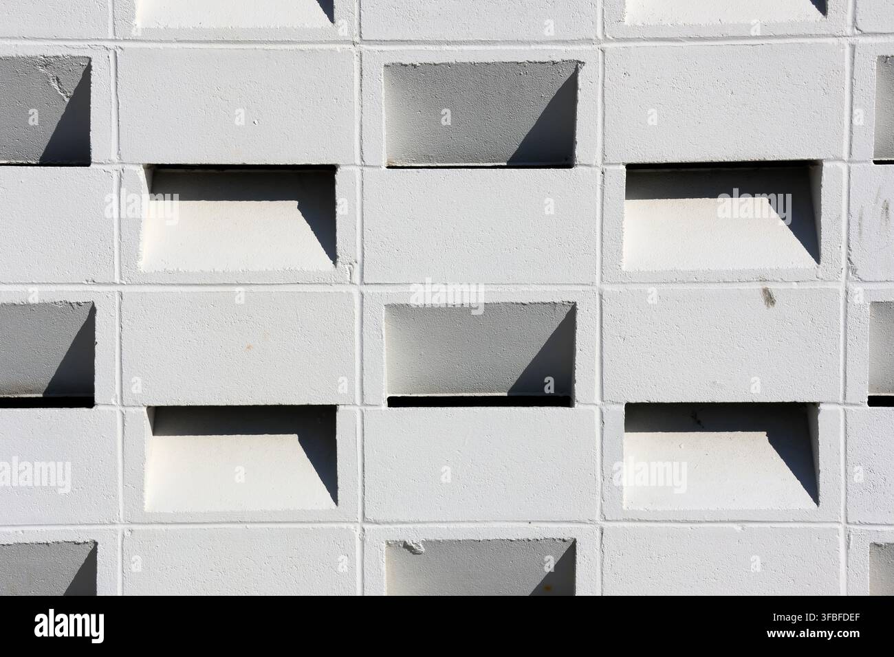 Sfondo a trama a cornice intera di un muro di blocchi di calcestruzzo bianco con forme geometriche pulite e ombre di luce solare forte Foto Stock