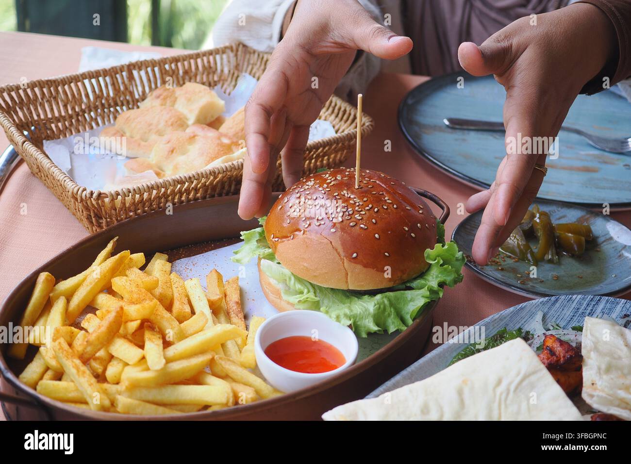 Mani pronte a godersi hamburger e patatine fritte Foto Stock