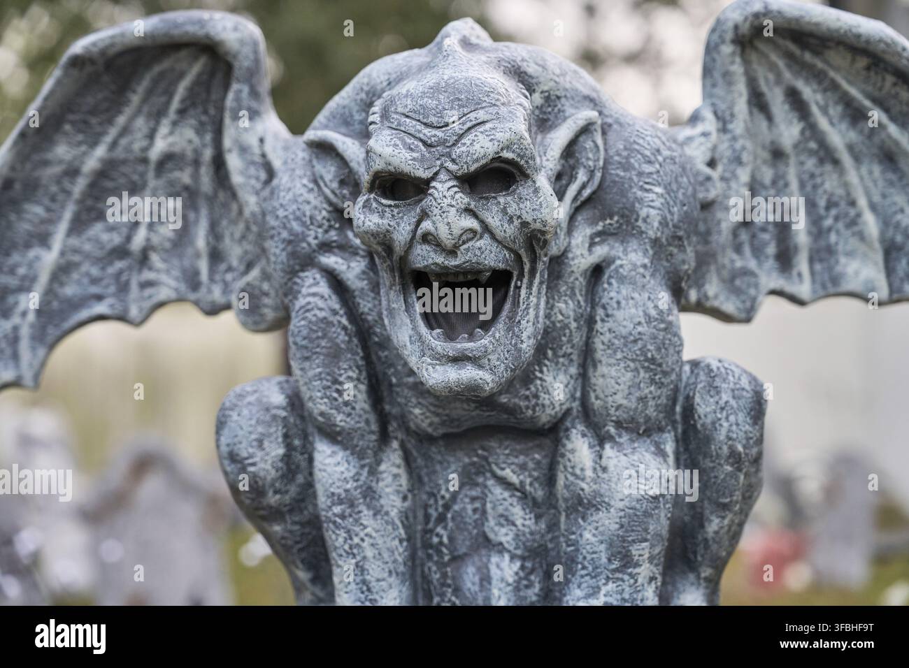 Una vista dettagliata di un gargoyle alato in pietra con bocca aperta e denti affilati. La texture erosa e lo stile gotico creano una spaventosa decorazione per Halloween Foto Stock