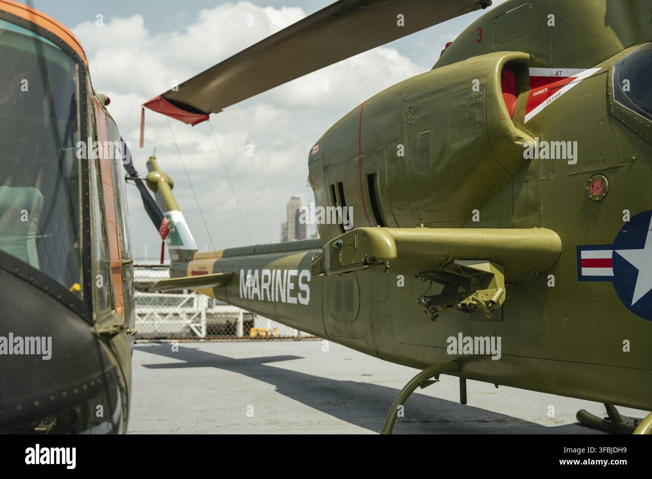 Retro di un elicottero militare verde contrassegnato MARINES su un ponte museale all'aperto. L'ala rotante, la coda e gli aerei circostanti sono visibili con c Foto Stock